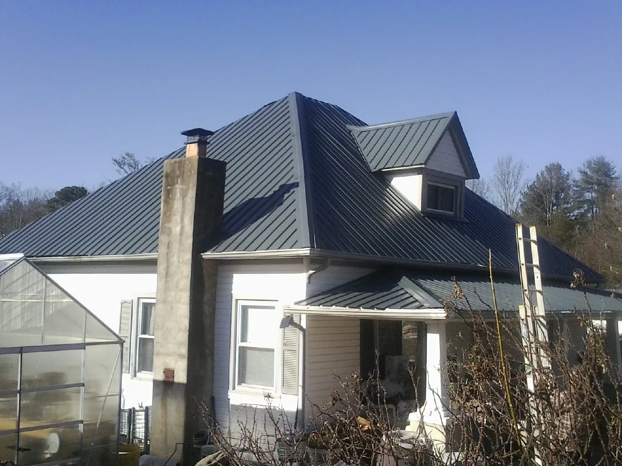 Dark blue standing seam metal roof on a white farmhouse with dormer — Slate & Tile Roof Repair by Roofing Brothers in Forman
