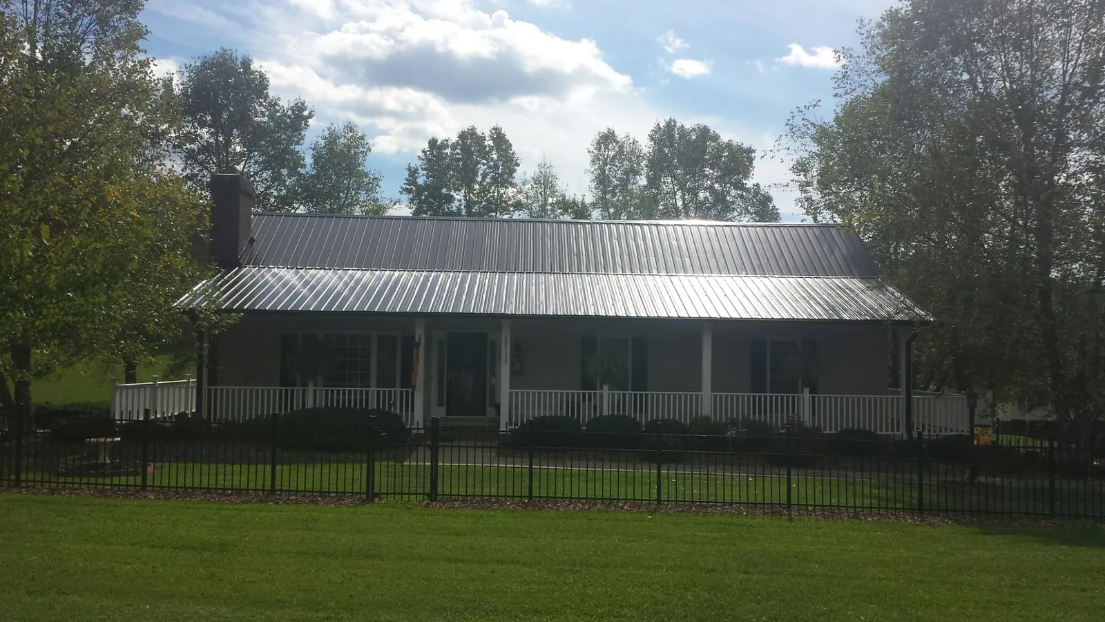 Gray metal roof on a brick ranch with a full width front porch — Gutter Guard Installation work by our crew in Forman
