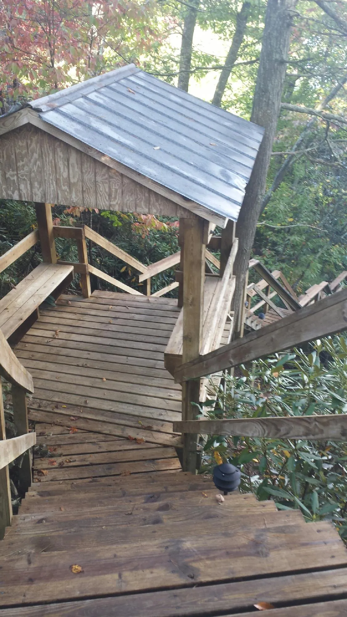 Metal roofed shelter over wooden steps on a wooded walkway — Skylight Repair & Installation work by our crew in Forman