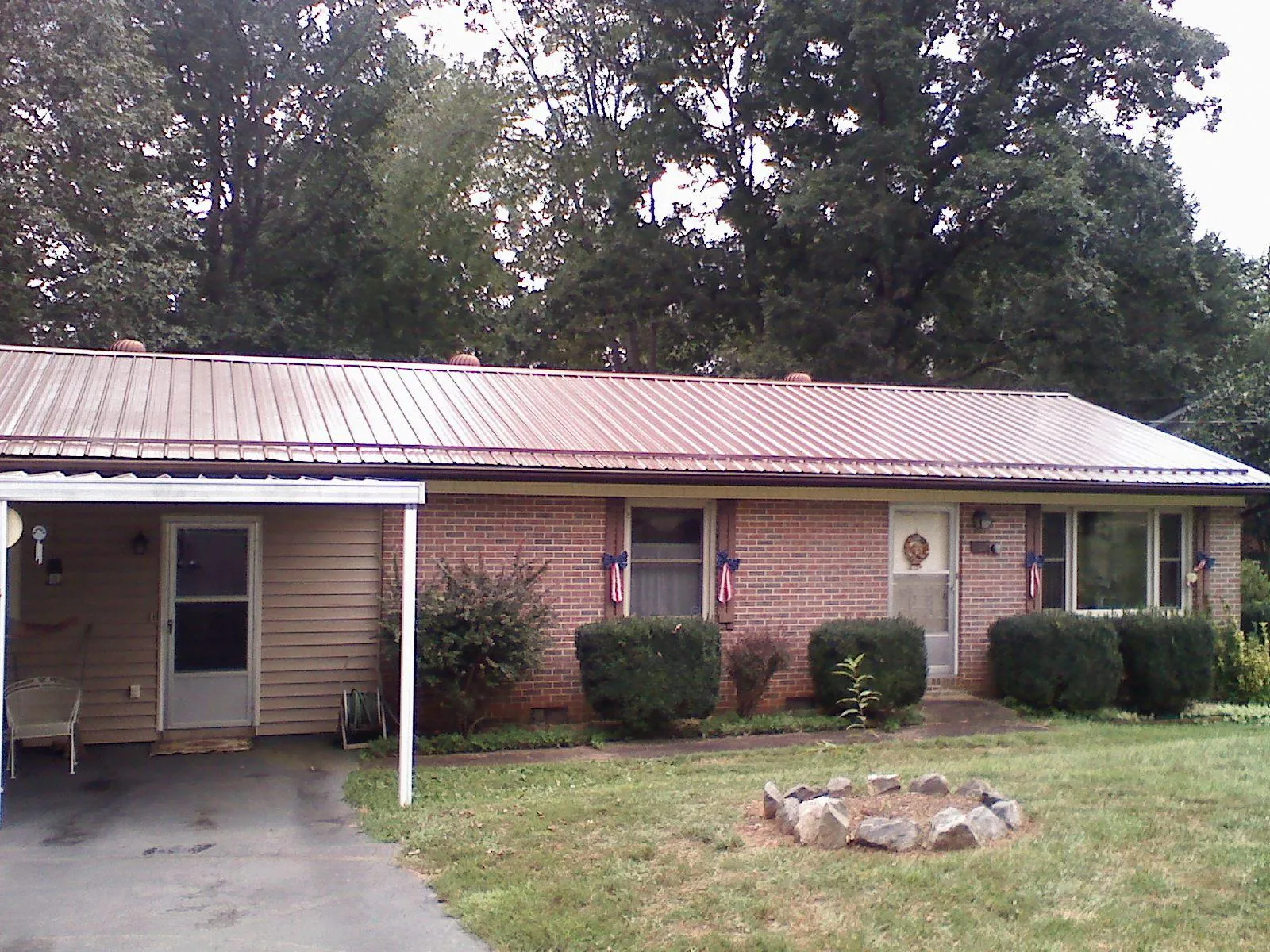 Bronze metal roof and carport on a brick ranch home — Roof Repair work by our crew in Forman